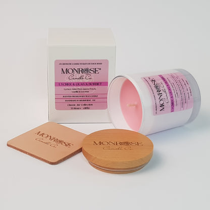 Side view of a container candle with "Lychee & guava sorbet" fragrance in white glass jar and a cotton wick, containing 185 grams of soy wax and offering 33 hours of burn time.