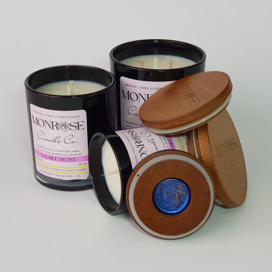 Front view of "Lychee peony" fragrance candle collection in black jars with cotton wicks.