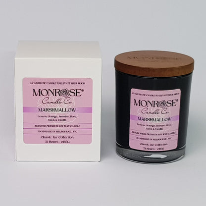 Front view of a container candle with "Marshmallow" fragrance in black glass jar and a cotton wick, containing 185 grams of soy wax and offering 33 hours of burn time.