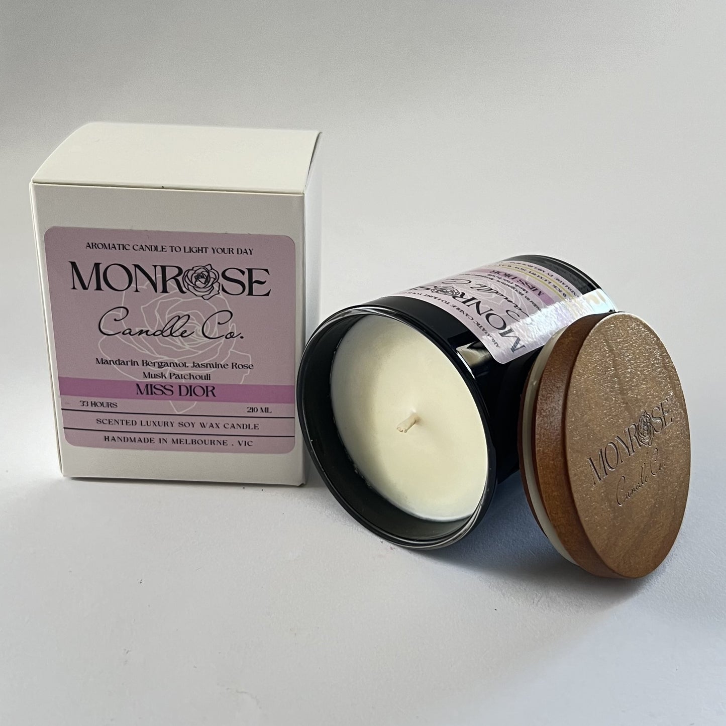 Side view of a black jar candle with "Miss Dior" fragrance and a cotton wick, containing 185 grams of soy wax and offering 33 hours of burn time.