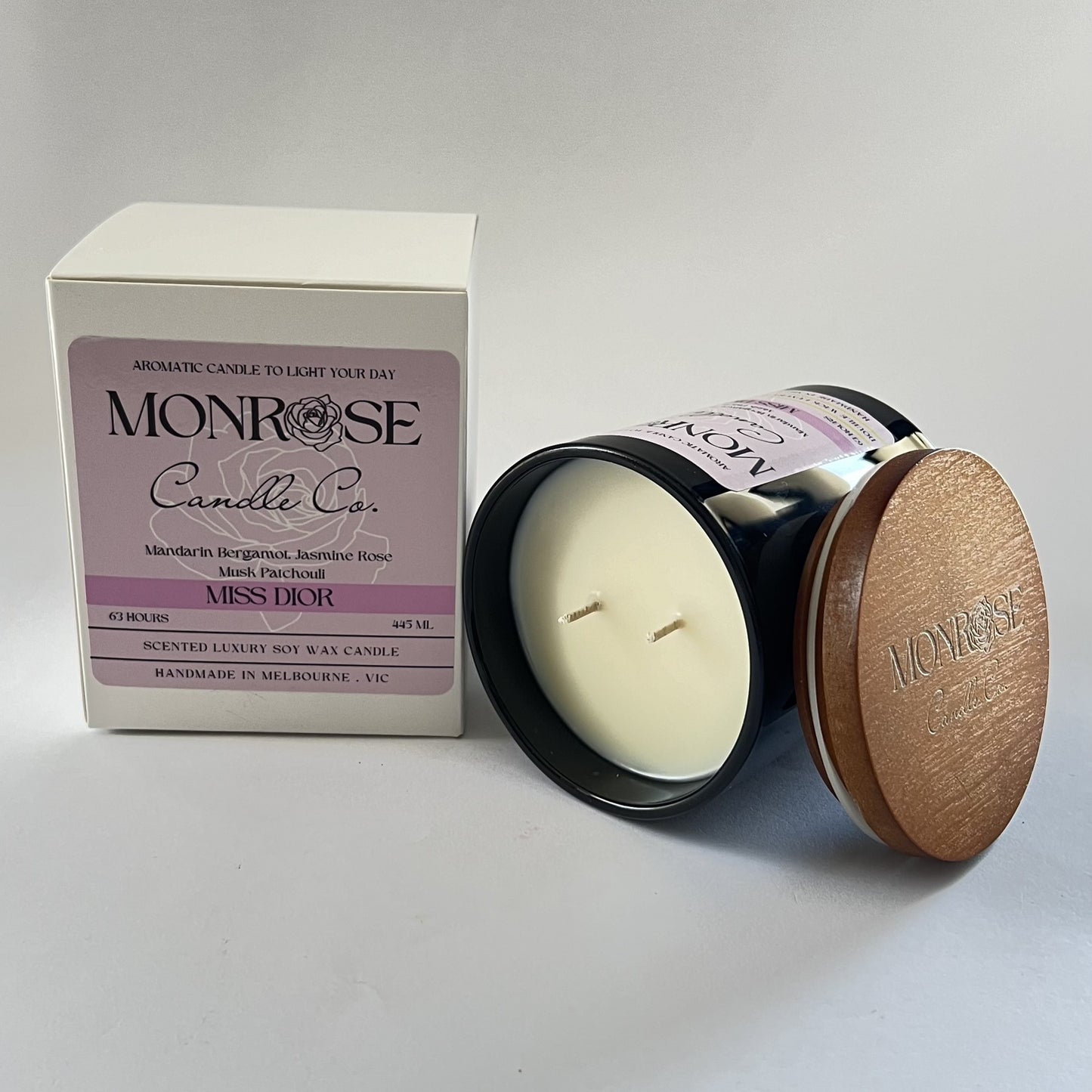 Side view of a black jar candle with "Miss Dior" fragrance and wood wick, containing 395 grams of soy wax and offering 63 hours of burn time.