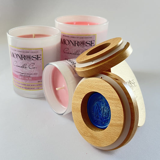 Front view of container candle collection infused with "Miss Dior" fragrance and in white jars with cotton wicks.