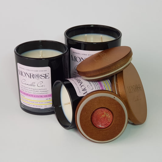 Front view of Pink champagne & exotic fruits fragrance candle collection in black jars with cotton wicks.