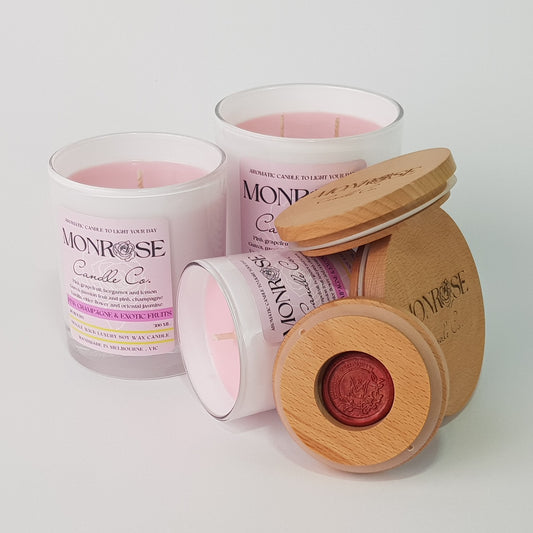 Front view of "Pink champagne & exotic fruits" fragrance candle collection in white jars with cotton wicks.