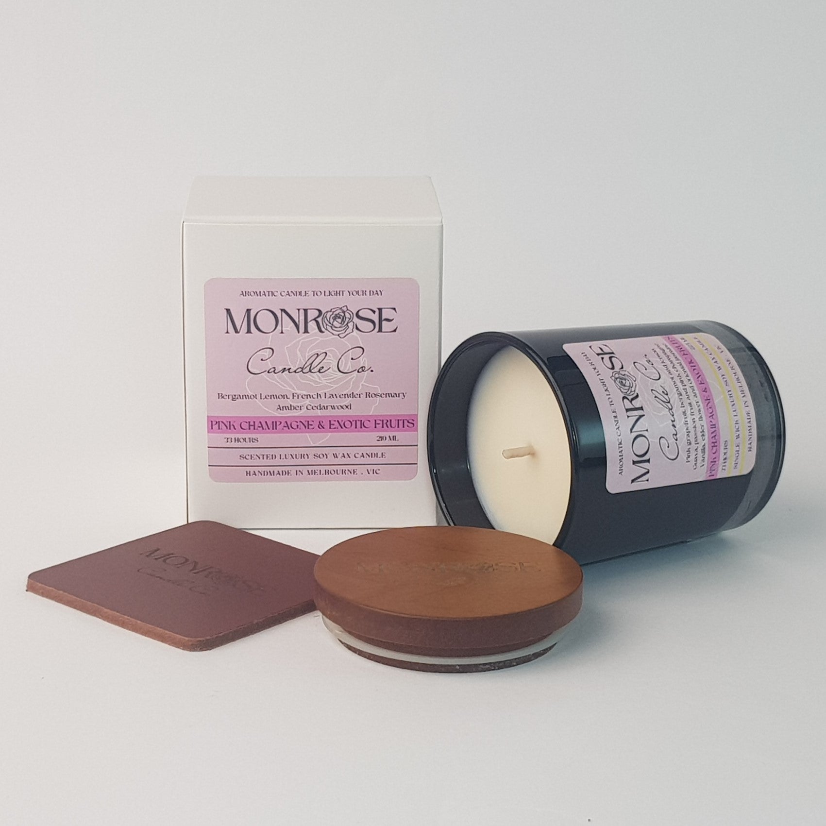 Side view of a black jar candle with 
"pink champagne & exotic fruits" fragrance and a cotton wick, containing 185 grams of soy wax and offering 33 hours of burn time.