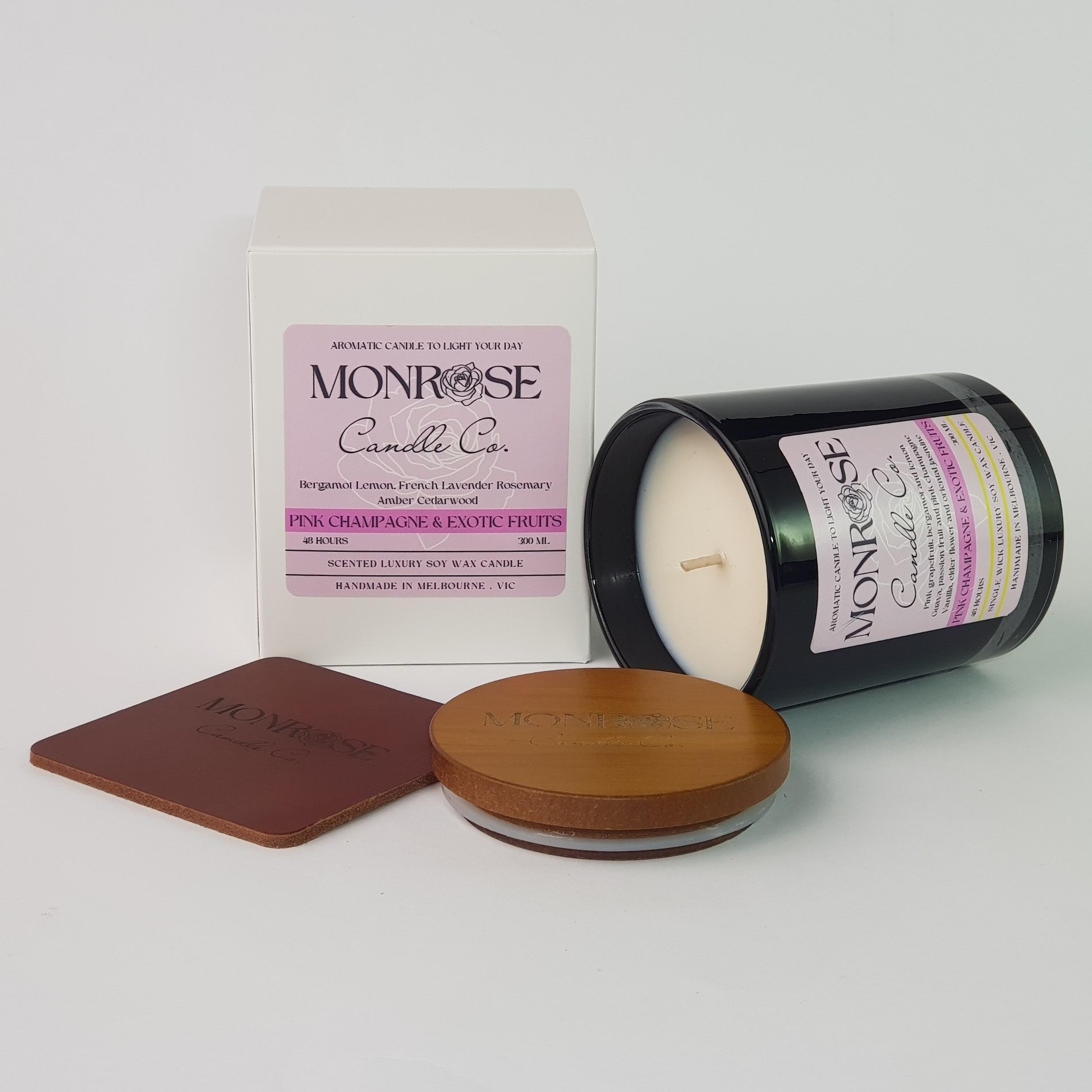 Side view of a black jar candle with "pink champagne & exotic fruits" fragrance and a cotton wick, containing 265 grams of soy wax and offering 48 hours of burn time.