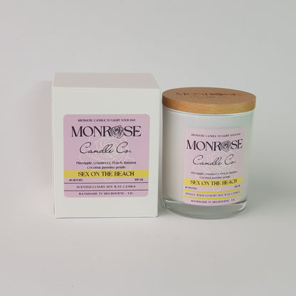 Front view of a white jar candle with "Sex on the beach" fragrance and a cotton wick, containing 265 grams of soy wax and offering 48 hours of burn time.