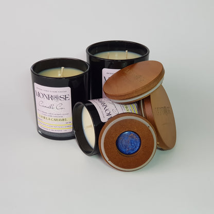 Front view of "vanilla caramel" fragrance candle collection in black jars with cotton wicks.