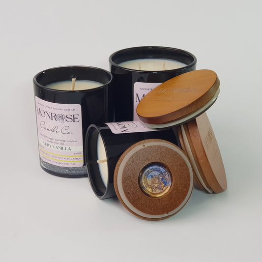 Front view of the "very vanilla" fragrance candle collection in black jars with cotton wicks. 