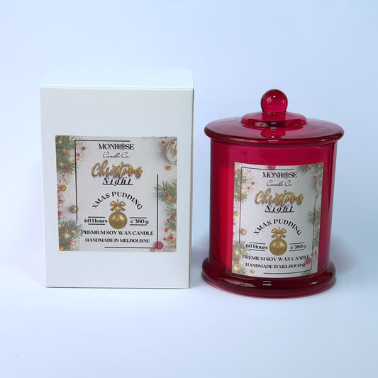 Front view of a red jar candle with 
"Christmas Pudding" fragrance and a cotton wick, containing 380 grams of soy wax and offering 60 hours of burn time.