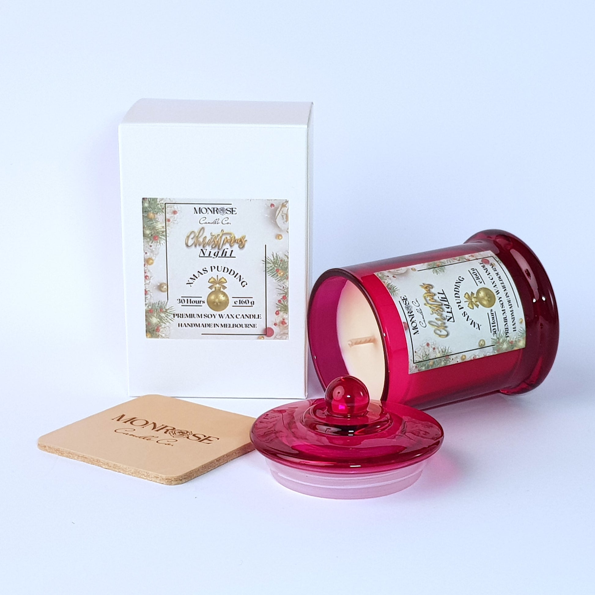 Side view of a red jar candle with 
"Xmas Pudding" fragrance and a cotton wick, containing 160 grams of soy wax and offering 30 hours of burn time.
