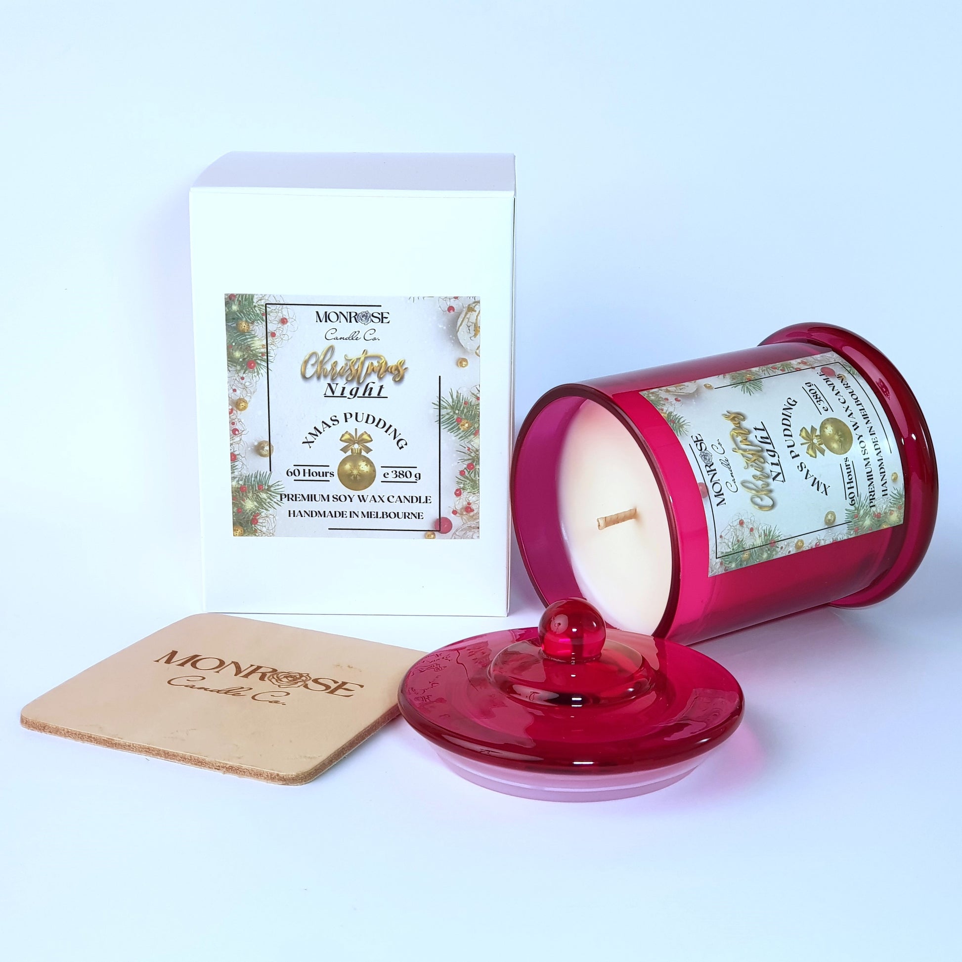 Side view of a scented candle in a red jar with "Christmas Pudding" fragrance and a cotton wick, containing 380 grams of soy wax and offering 60 hours of burn time.
